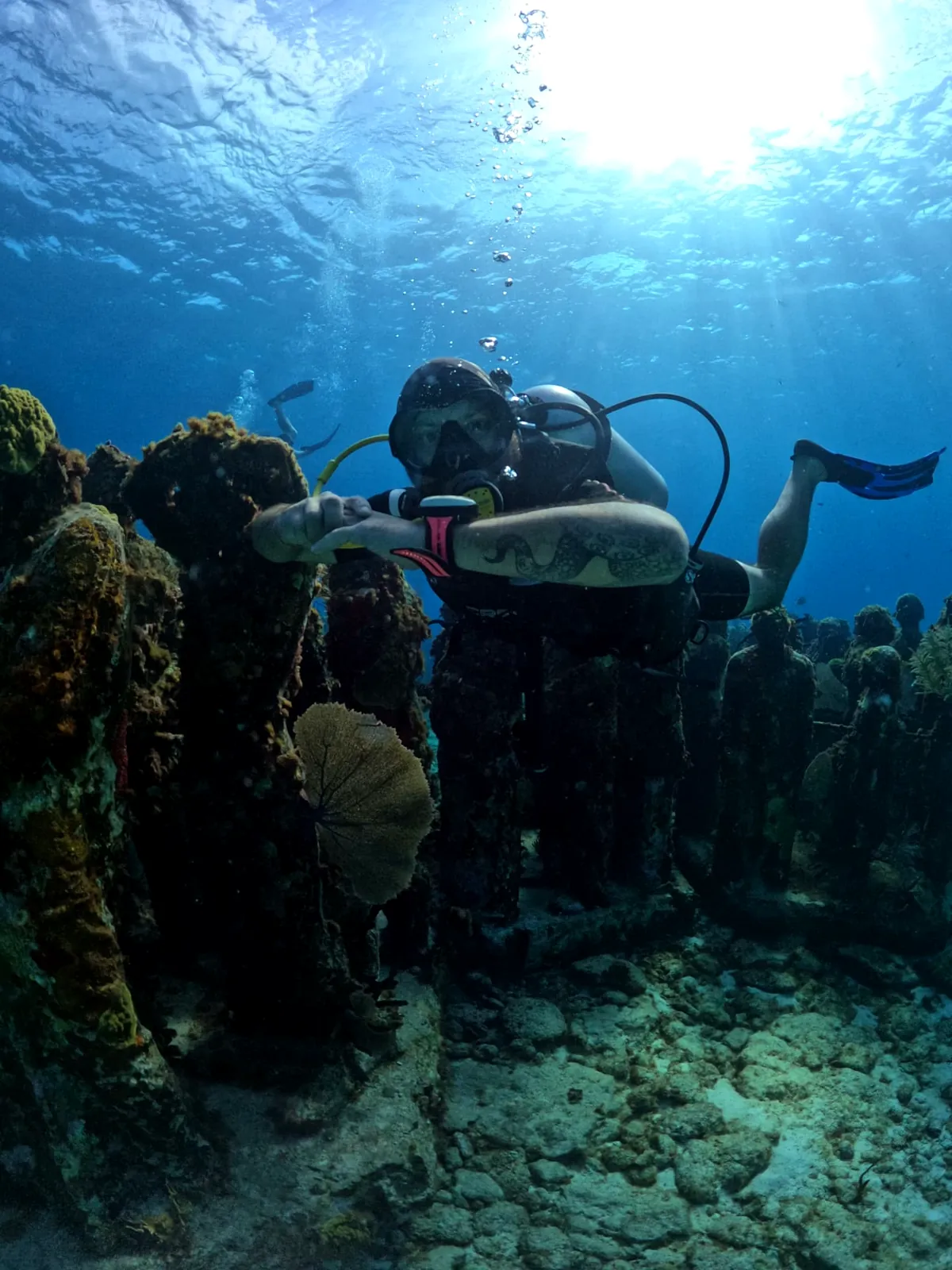 Diver posing among the MUSA sculptures in sunlit water