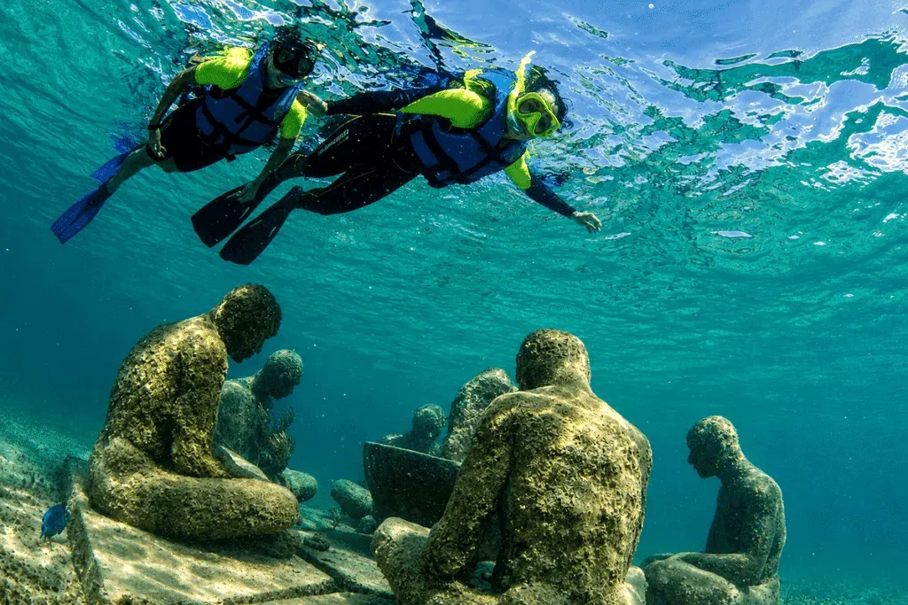 Snorkelistas con chaleco observando esculturas submarinas