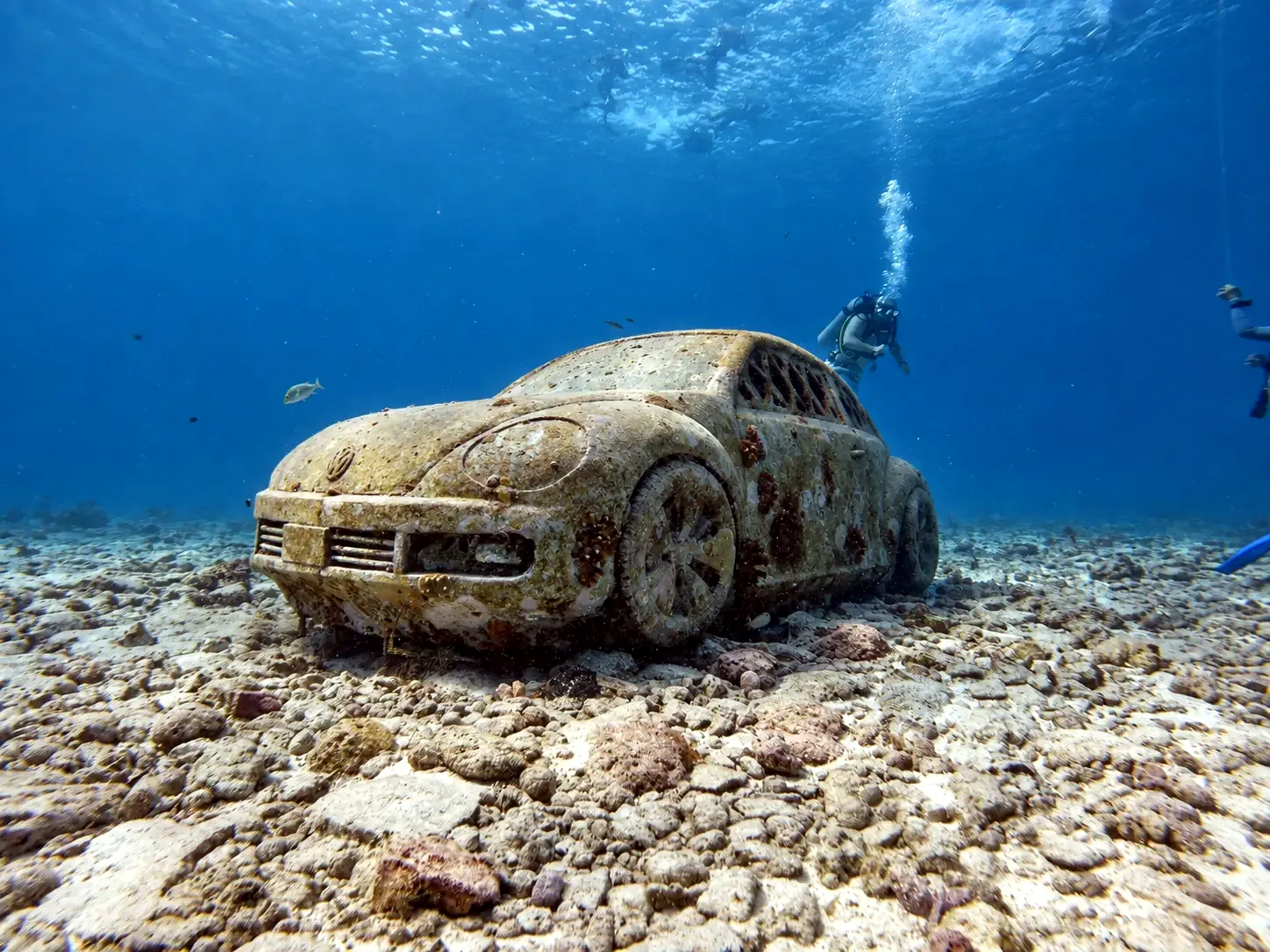 VW Beetle sculpture on the seabed with a diver behind it